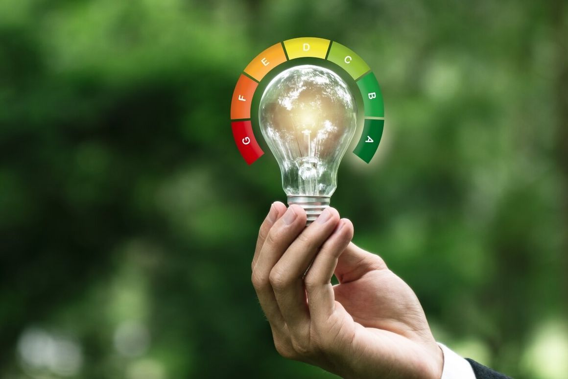 Hand hält Glühbirne mit Energieeffizienzklassen